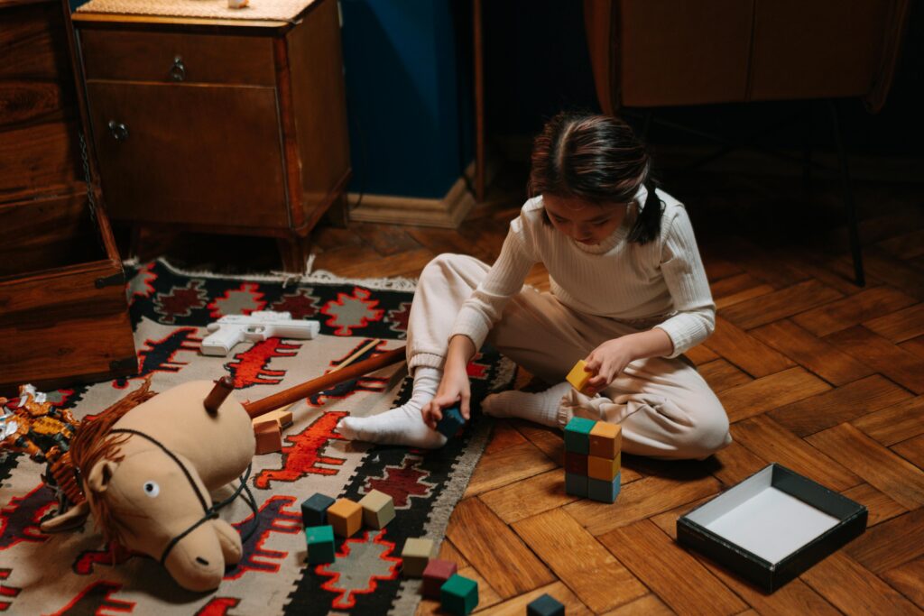 A child playing with toys on a wooden floor, much like how one can play with their brand.