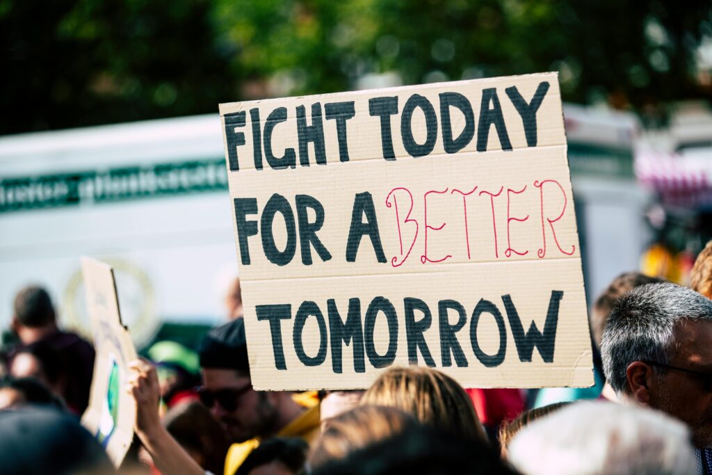 A protest sign being held up within a crowd, saying "Fight today for a better tomorrow".