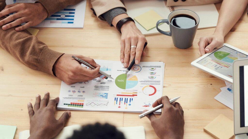 Group of diverse professionals analysing graphs and charts during a business meeting, focusing on marketing strategy and data-driven decision making